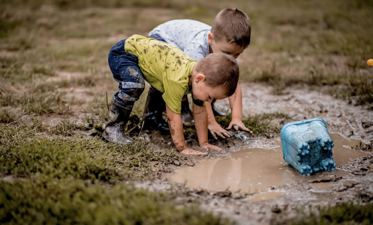 Young children playing outdoors in natural green space with plants and soil