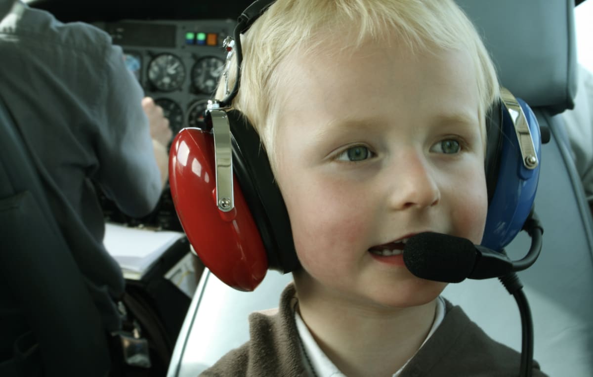 Five-year-old boy sitting in commercial airplane flight simulator during tour of training facility