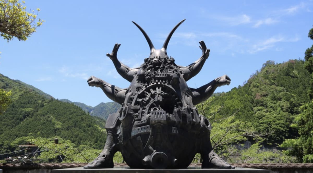 Giant bronze cockroach statue with muscular arms posed dramatically outside Japanese temple