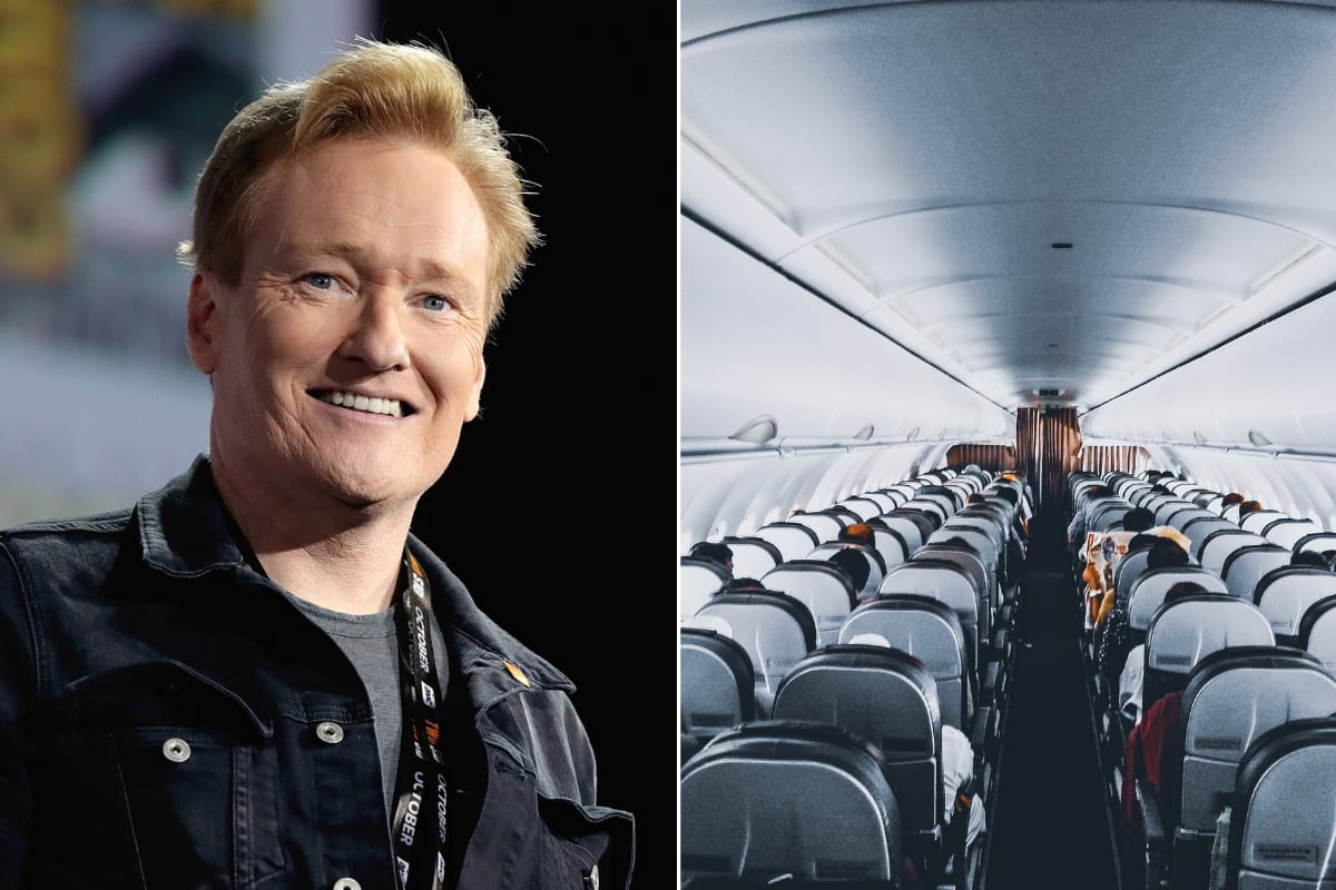 Conan O'Brien smiling while walking through a commercial airport terminal with travelers