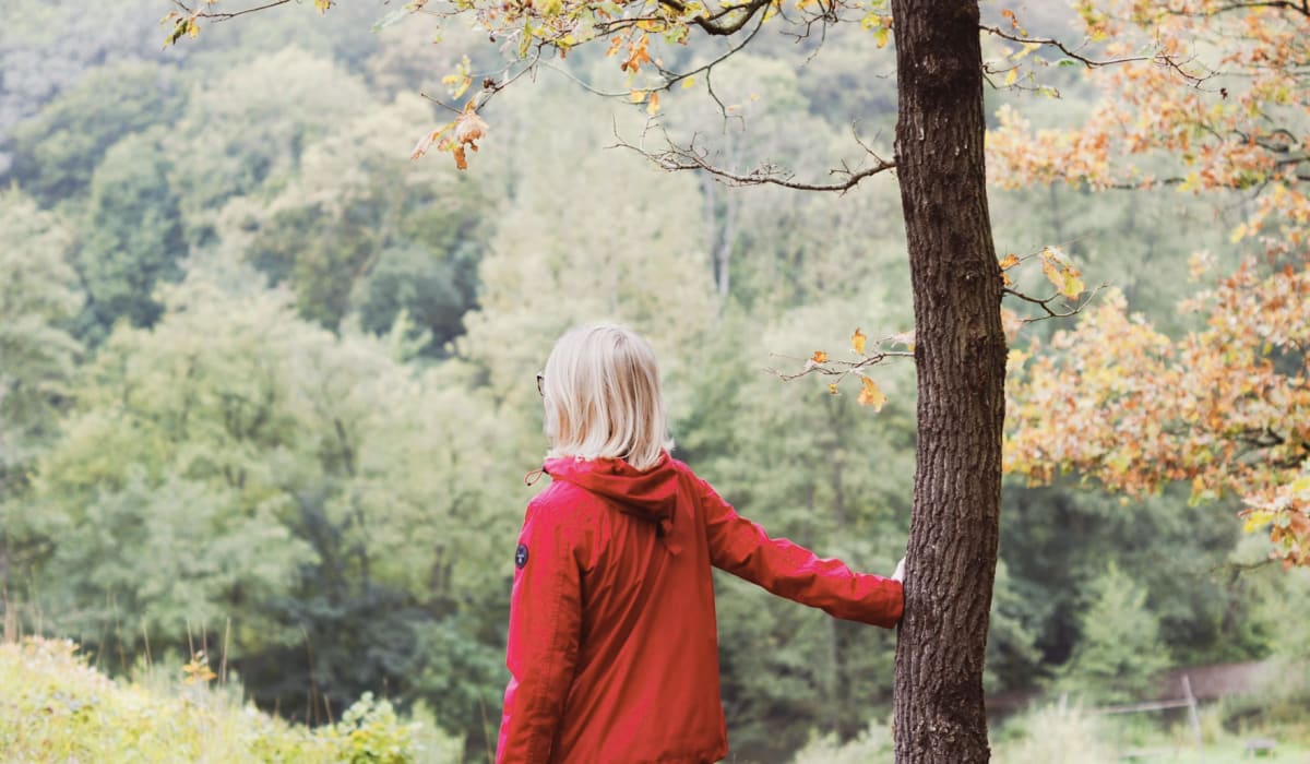 Molly Burke reaching out to touch a tree in a park while using echolocation
