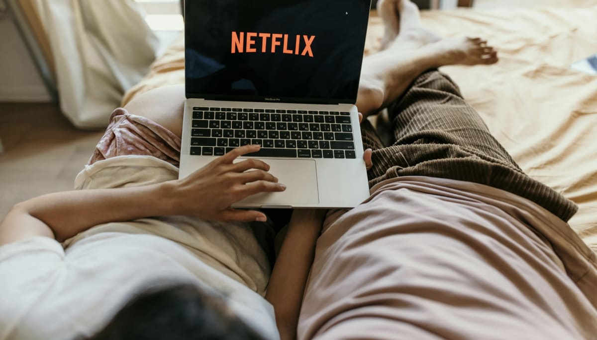 Woman smiling while logging into streaming service on laptop at home