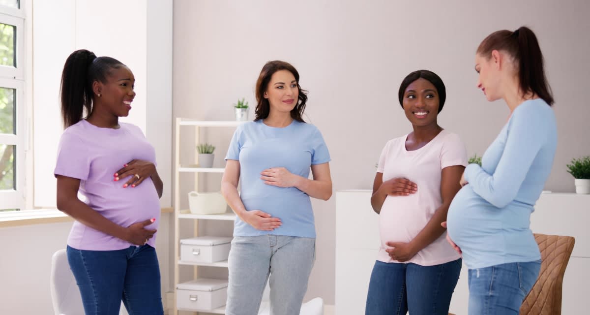Fifteen pregnant nurses in blue scrubs standing together showing baby bumps at Miami Valley Hospital