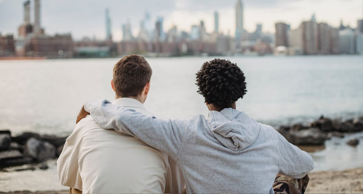 Two close friends sitting together on a beach sharing an honest conversation