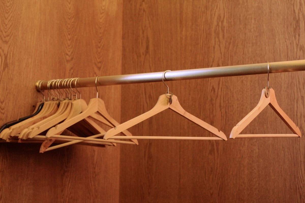 Flight attendant checking hotel room with coat hanger near window curtains for safety