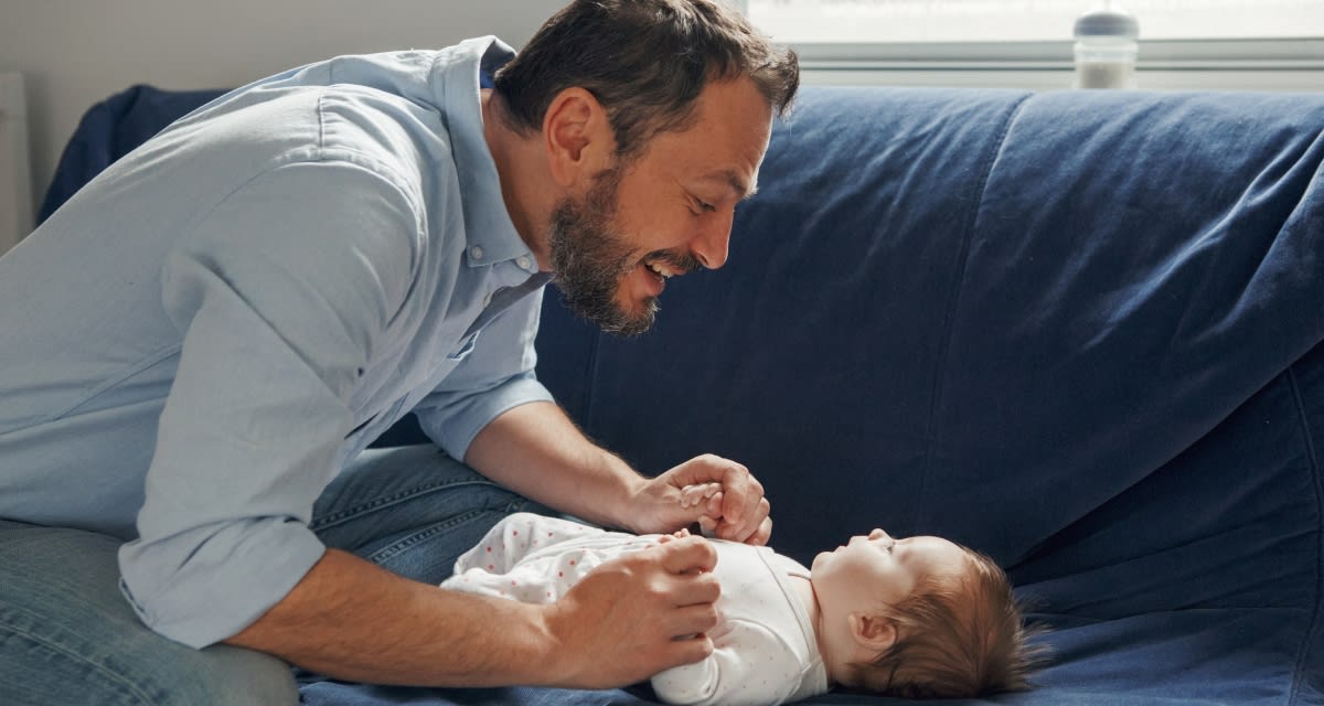 Parent leaning close to smiling infant baby using animated facial expressions while talking