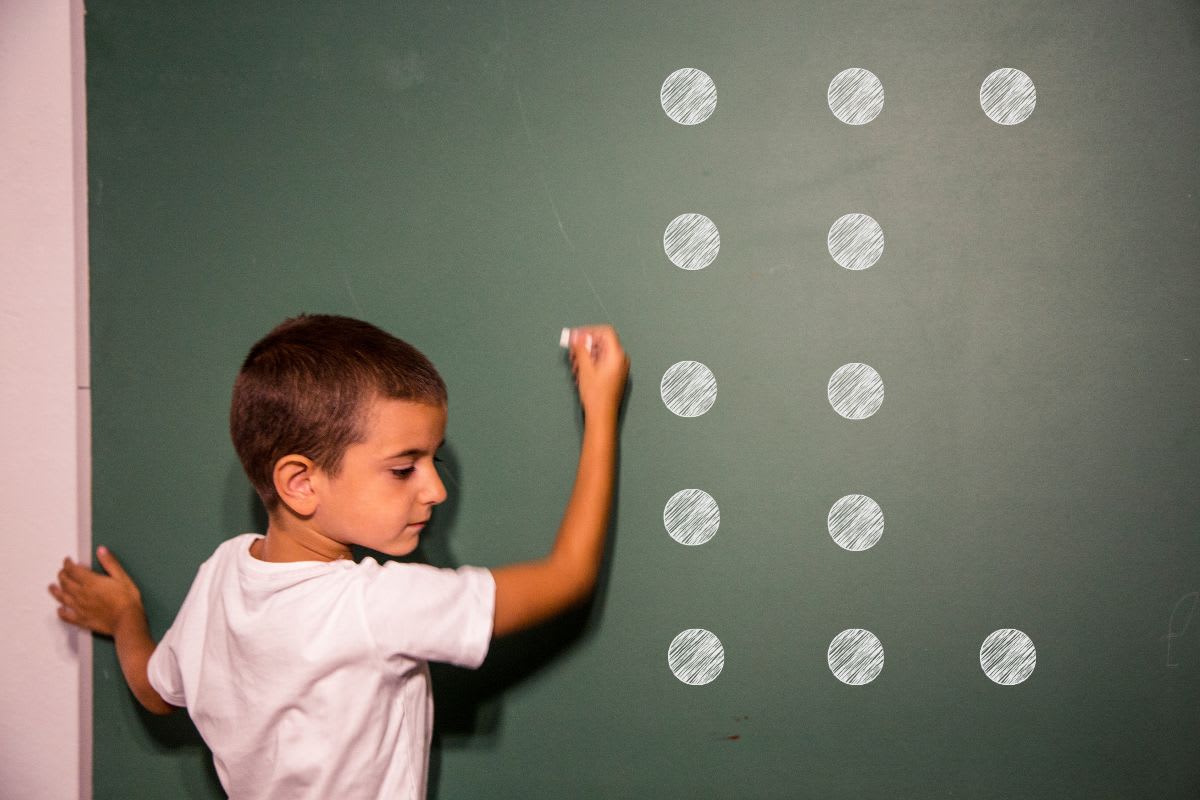 Student using chalk to connect dots on a classroom chalkboard during brain teaser challenge