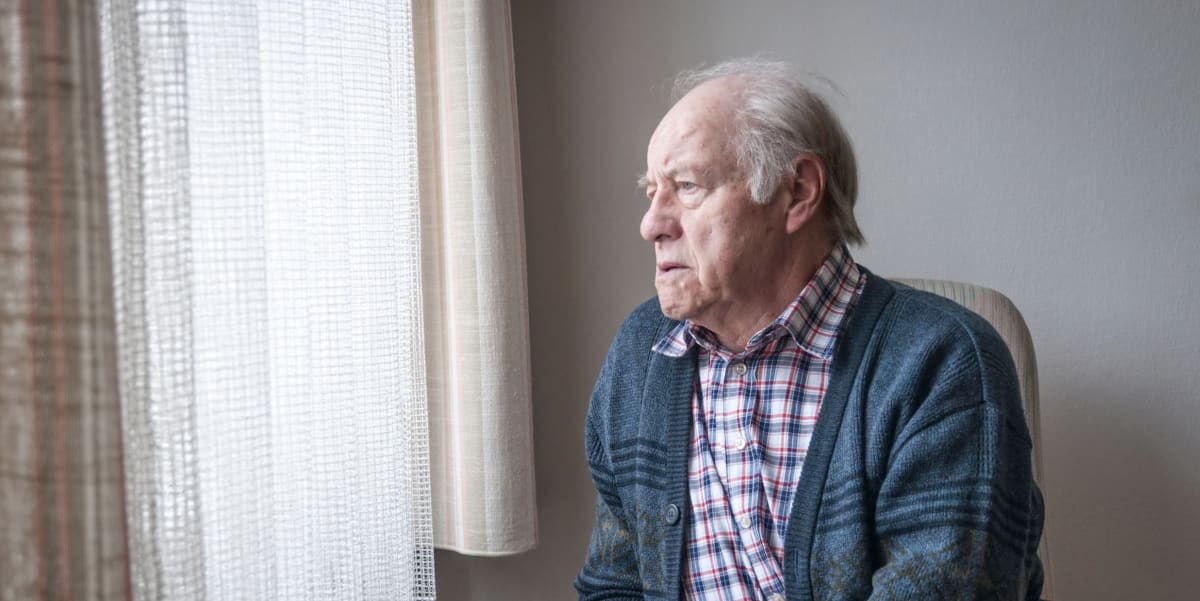 Elderly man being comforted by caregiver in peaceful home hospice setting