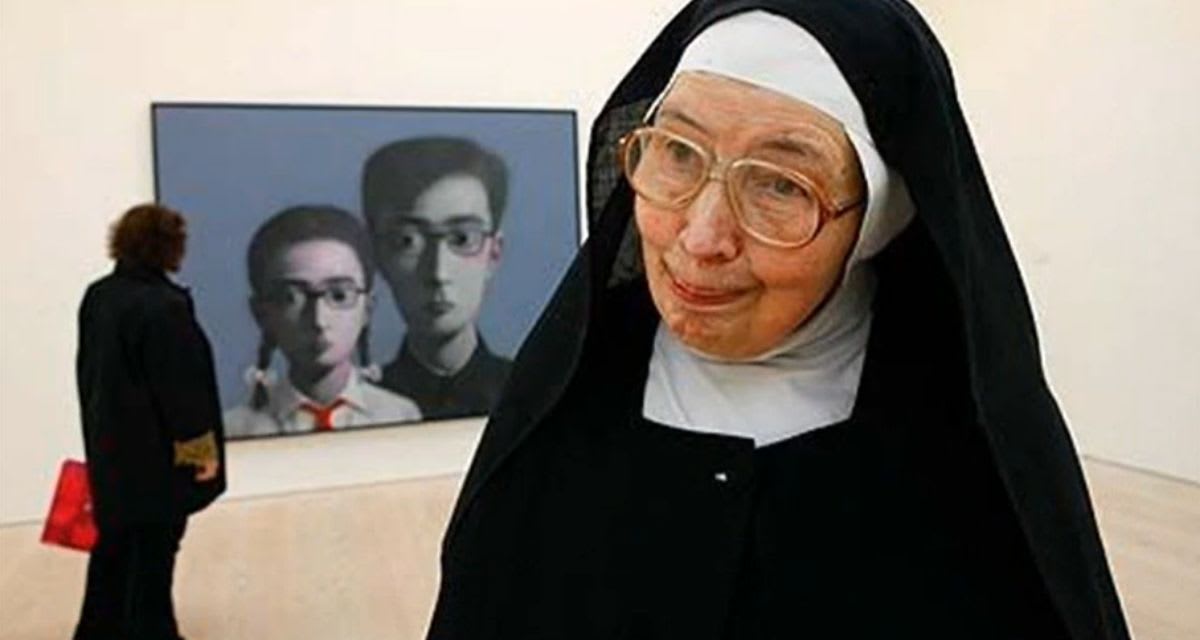 Sister Wendy Beckett in her nun's habit standing beside a large painting in an art gallery