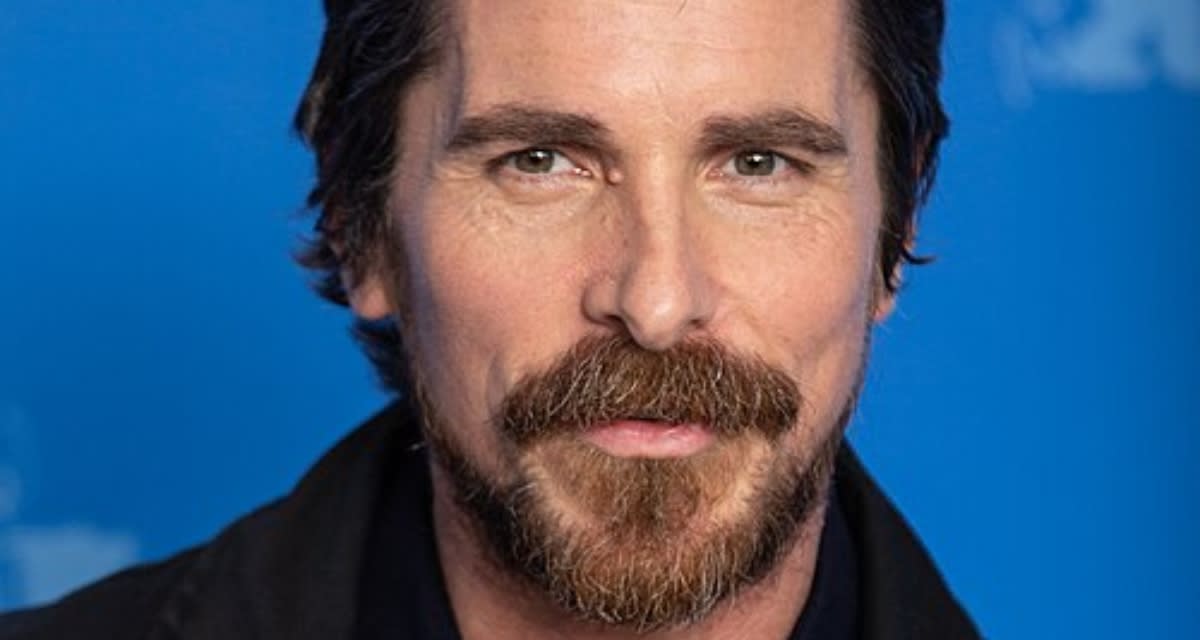 Christian Bale standing at Together California foster care village with residential homes visible behind him