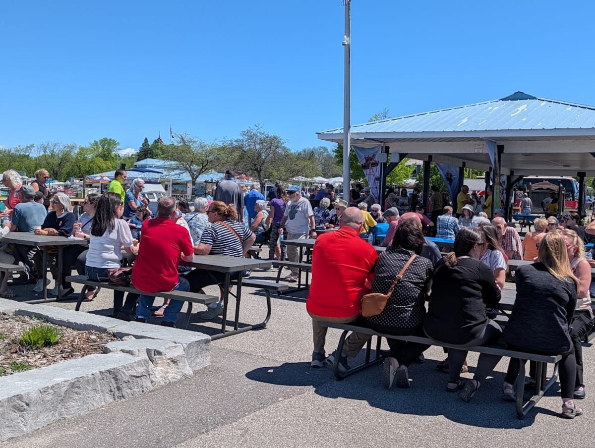 Volunteers serving free hot dogs and coffee to community members at sunny waterfront barbecue event