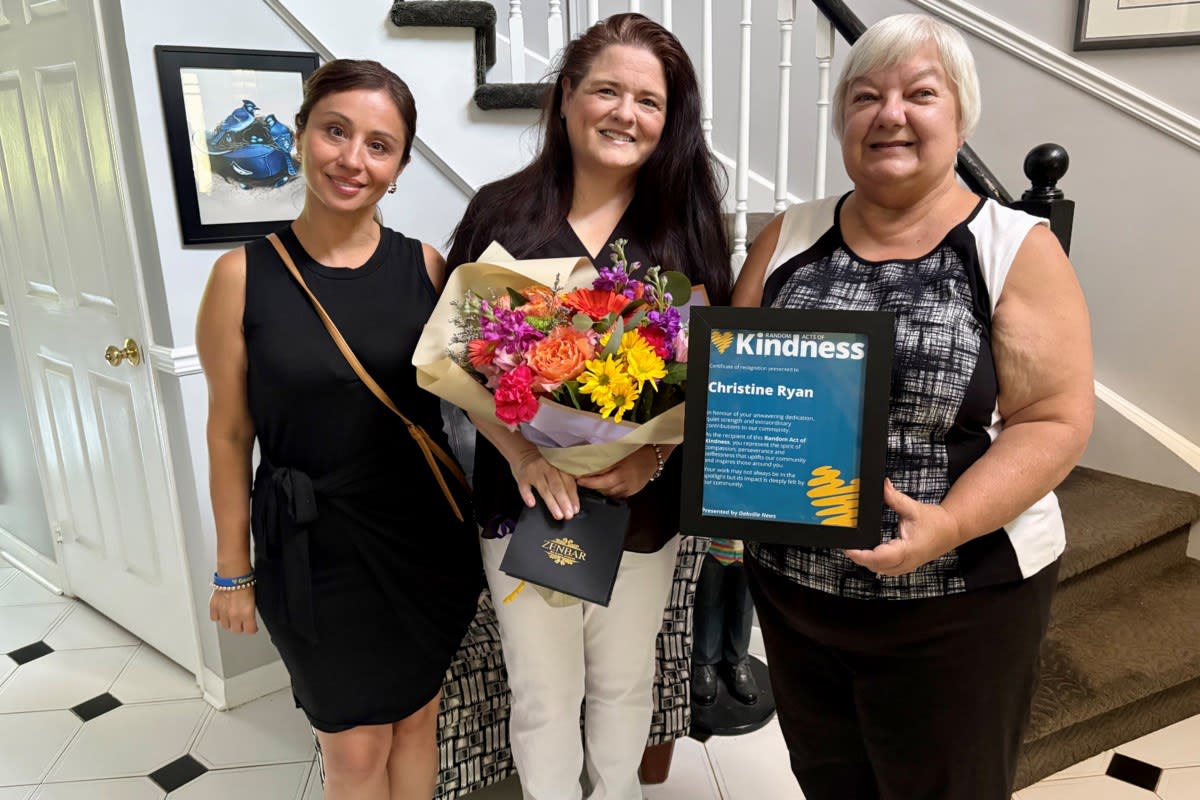 Woman smiling while holding bouquet of flowers after receiving community kindness award in Oakville