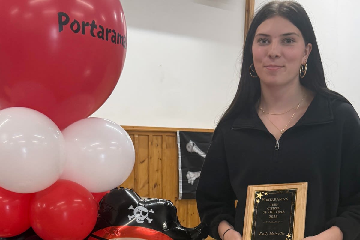 Teenage girl smiling while holding community service award plaque at outdoor festival celebration