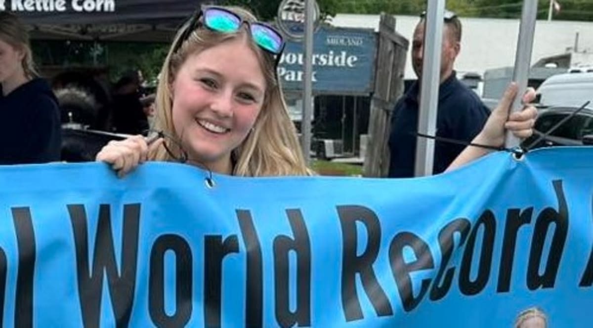 High school students holding open yearbook collecting signatures from community members at outdoor festival