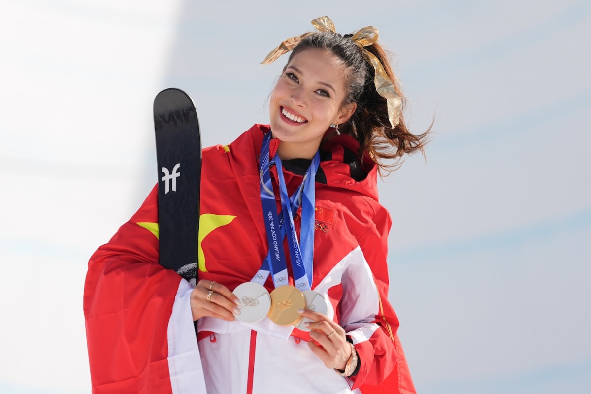 Eileen Gu celebrating on halfpipe podium with gold medal and championship trophy