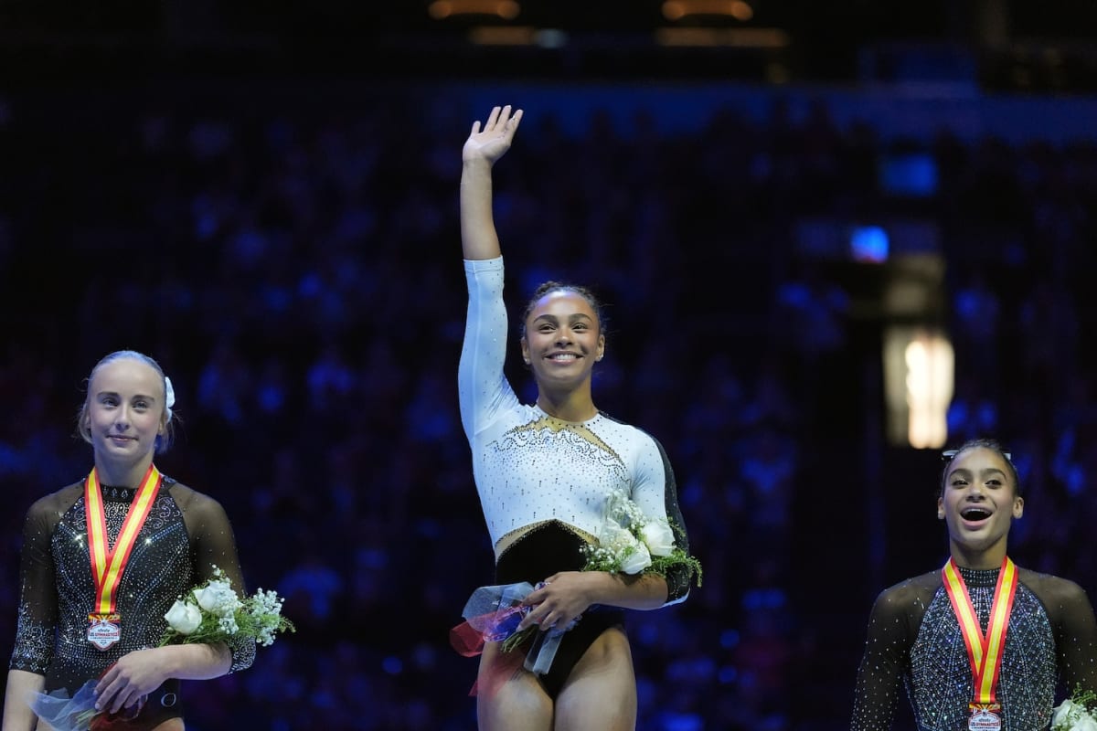 Olympic athletes celebrating with medals on podium waving to cheering crowds