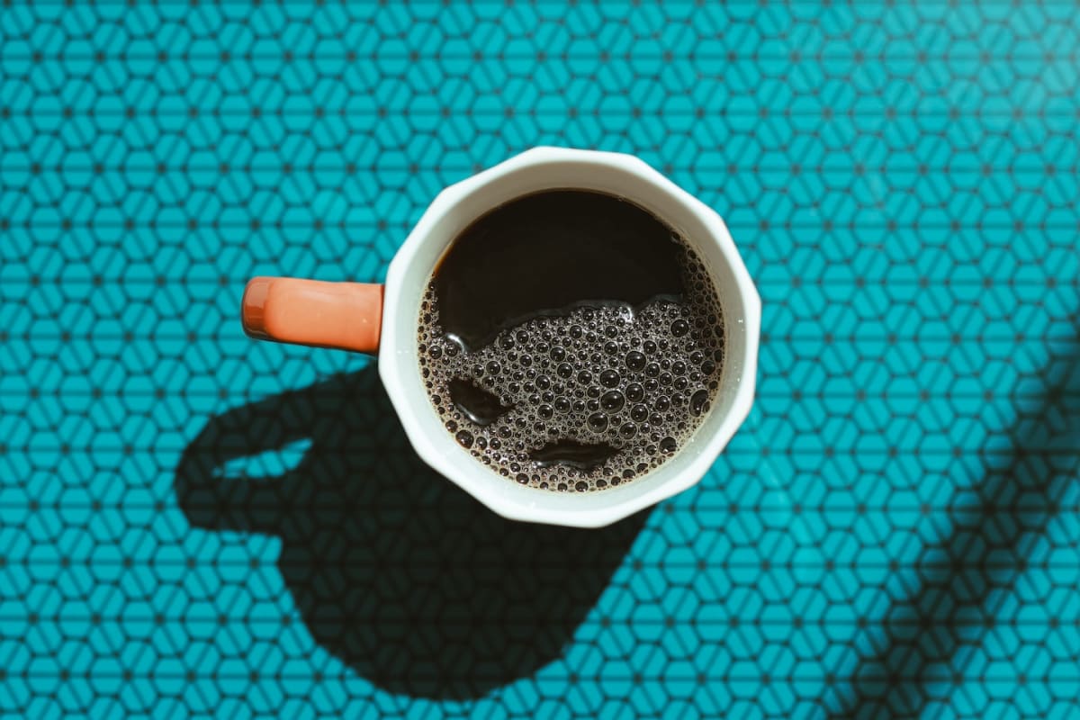 Steaming cup of fresh brewed coffee on morning table in natural sunlight