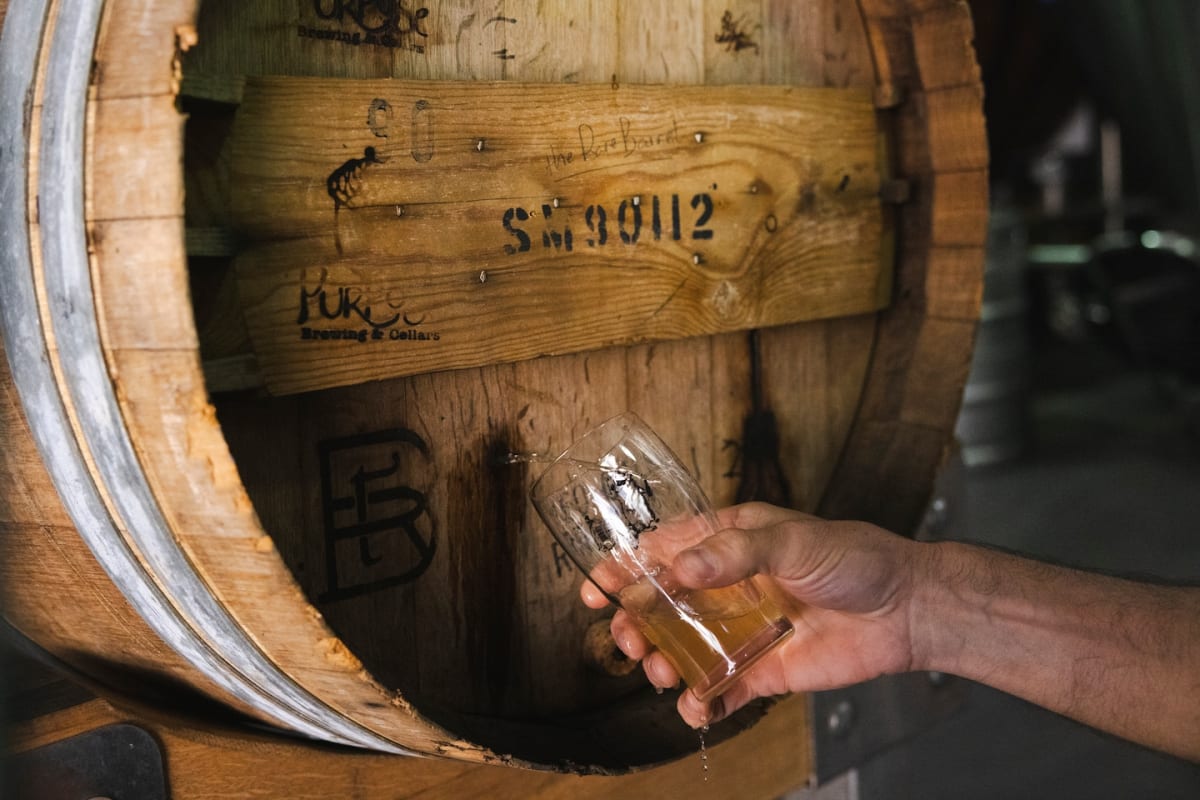 Oak barrel covered in 56 brewery logo brands collected over 30 years of traveling