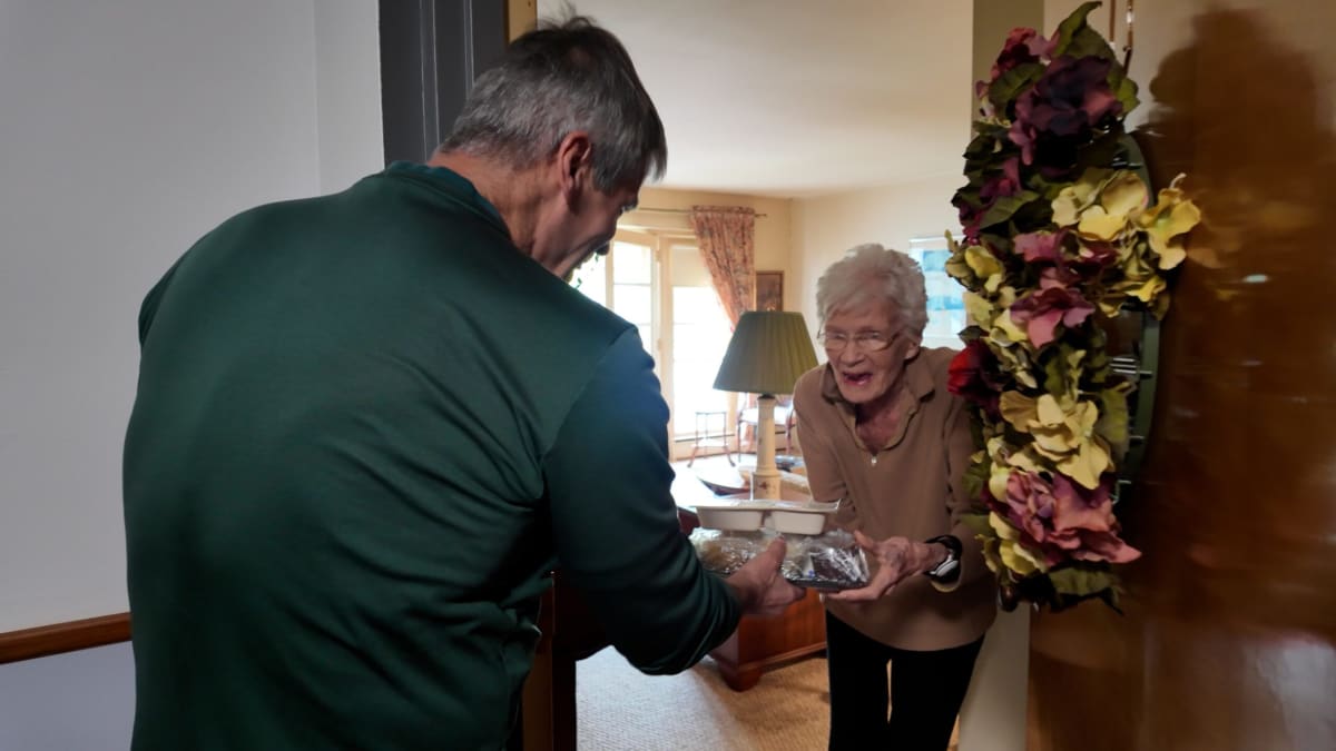 Meals on Wheels volunteer Dave Wideman delivering hot meal to senior citizen at home