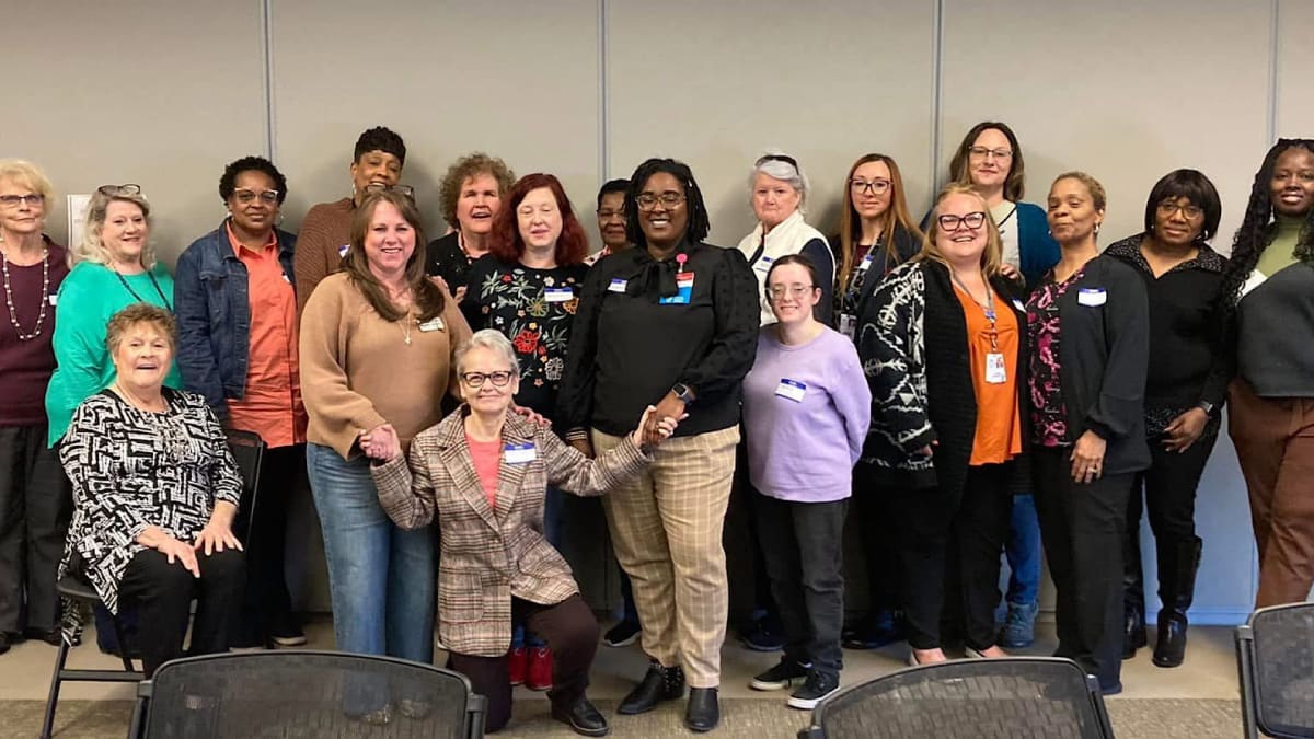 Senior adult smiling while receiving friendly assistance from volunteer in home setting