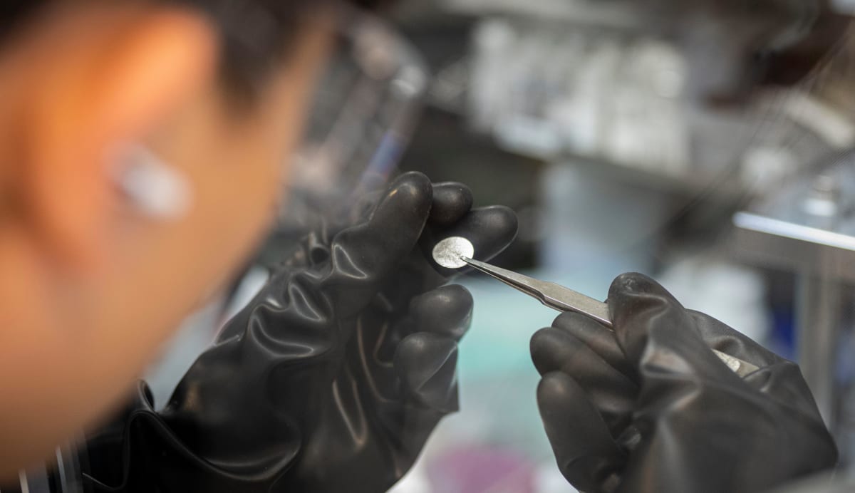 Scientist in laboratory examining lithium-ion battery components for recycling and upcycling research
