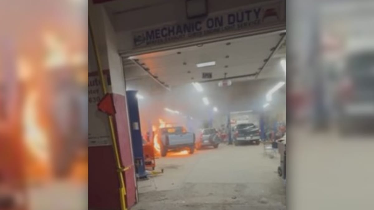 ** Firefighters examining damaged GMC Hummer EV after battery fire at Providence auto repair shop