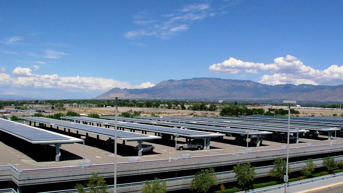 Solar panels and wind turbines generating renewable electricity across New Mexico's sunny desert landscape