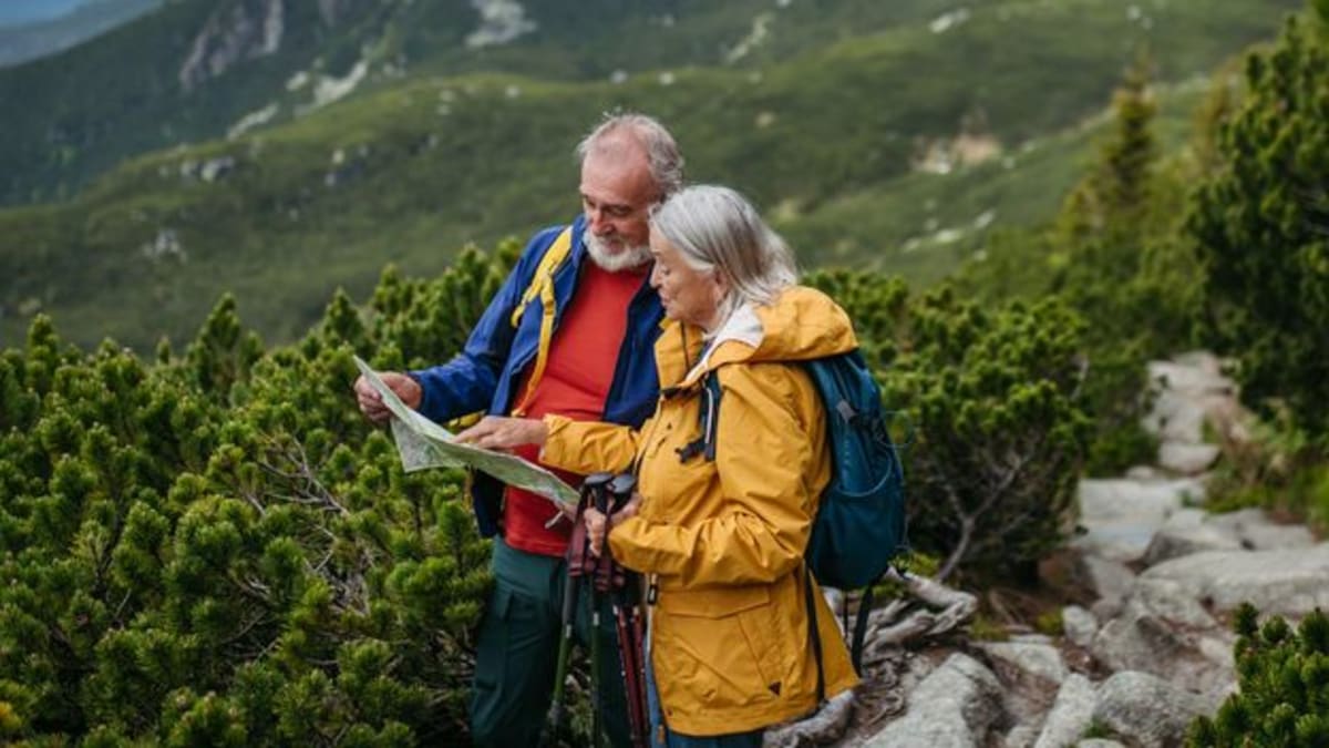 Senior adult reading map outdoors while hiking, practicing spatial navigation for brain health