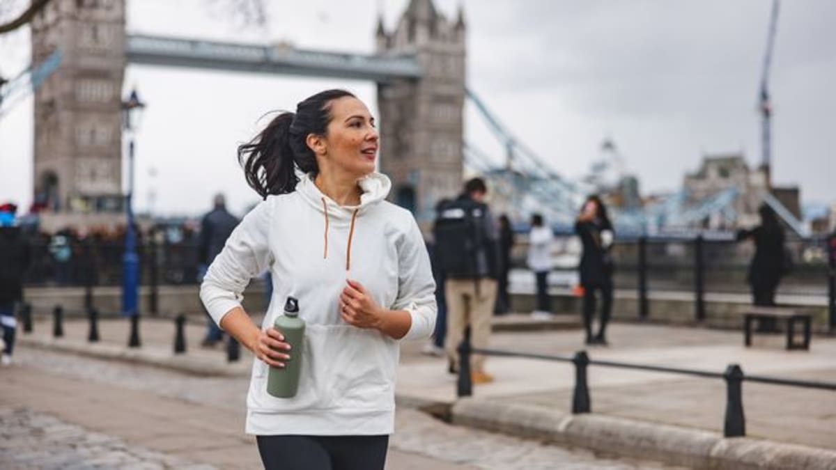Person jogging on city street with urban buildings in background