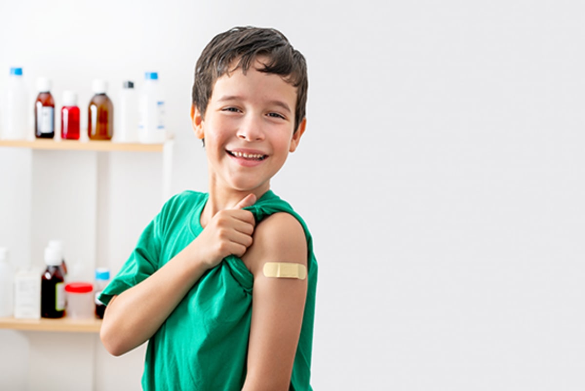 Pediatrician administering vaccine to smiling child while parent watches supportively in medical office
