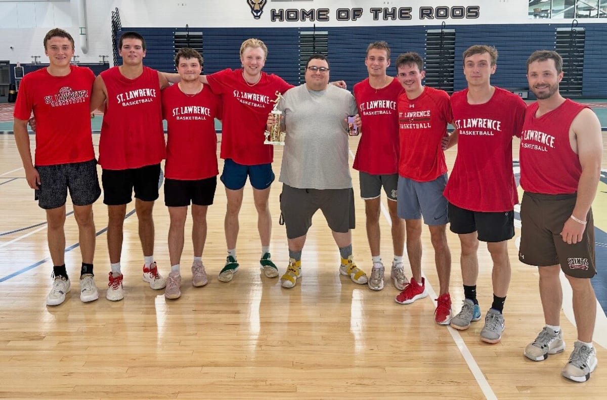 Basketball team celebrating together on court after winning summer league championship game