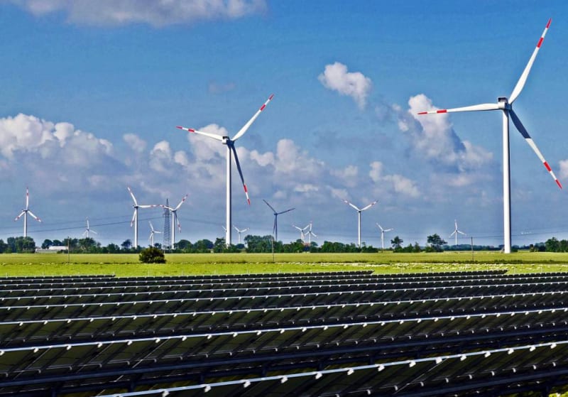 Solar panels and wind turbines generating clean renewable energy under bright blue sky