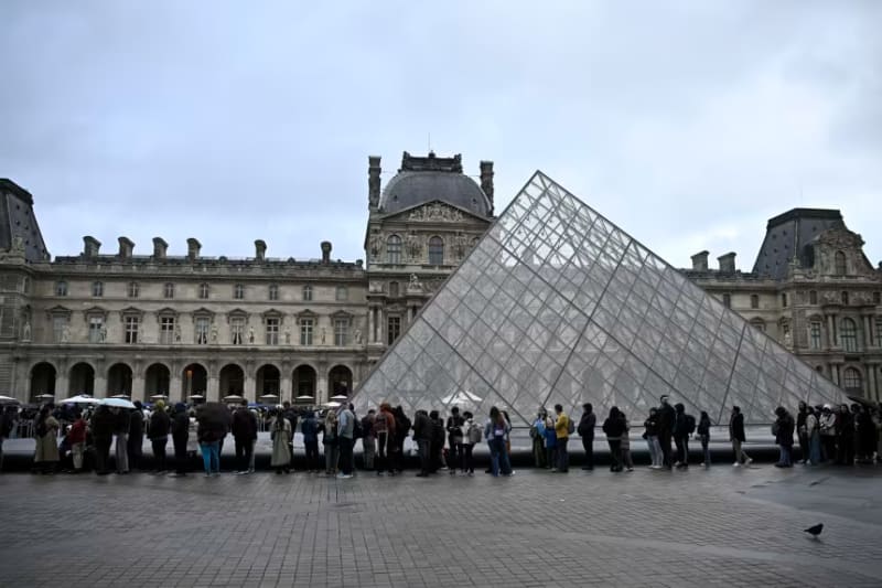 Visitors lined up outside the iconic glass pyramid entrance of the Louvre Museum in Paris