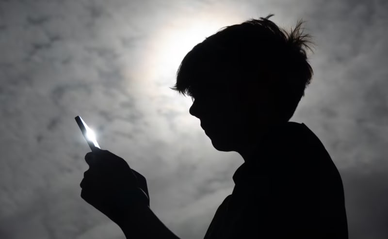 Parent and teenager looking at smartphone together discussing screen time limits and app settings