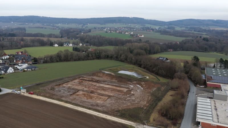 Archaeologists examining ancient pottery fragments inside excavated Iron Age settlement pit in Germany