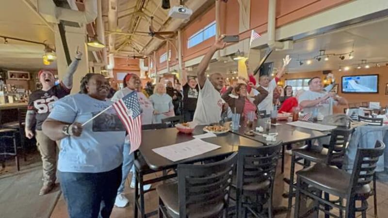 Family and friends cheering at restaurant watch party for Olympic bobsledder Jasmine Jones