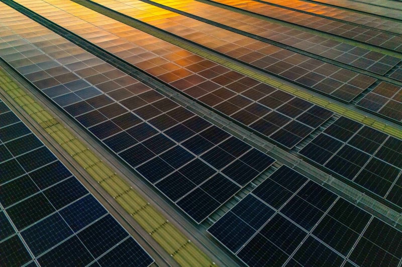 Solar panels and wind turbines stretching across landscape under bright blue sky