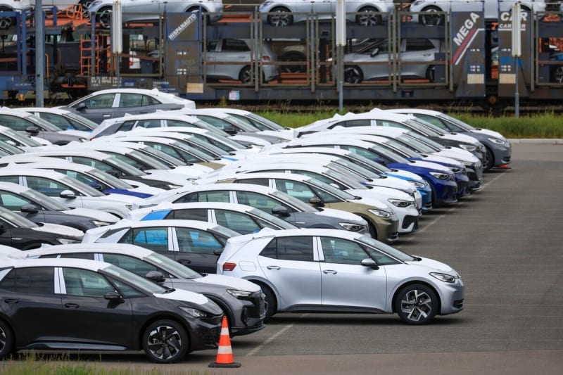 Modern electric vehicles charging at European station with customers browsing new cars nearby
