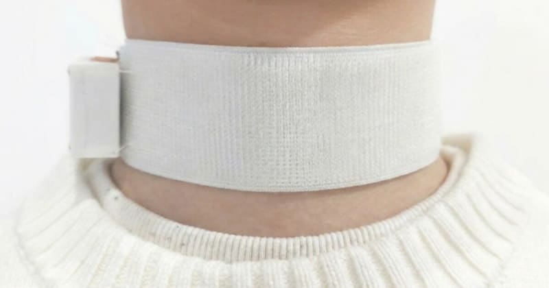 Stroke survivor wearing soft black Revoice choker device with integrated throat sensors around neck