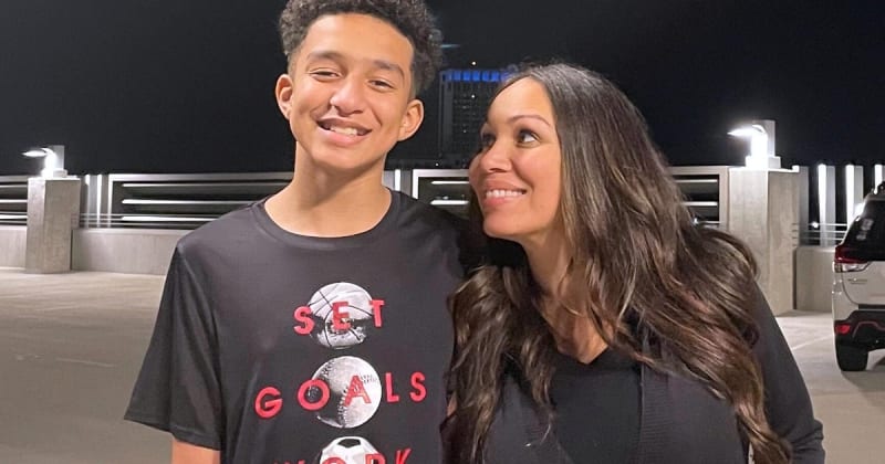 Mother and teenage son standing together smiling, representing family connection and the importance of protecting young people online