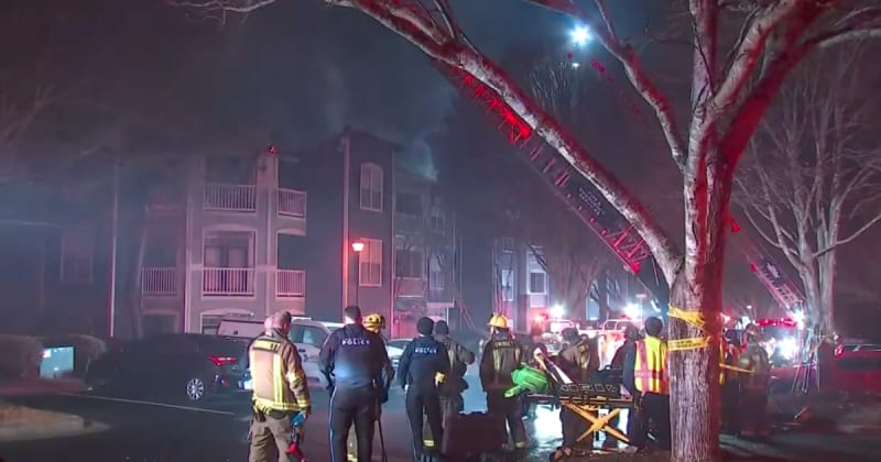 Firefighters battling apartment building fire with aerial ladders extended at night in Gwinnett County