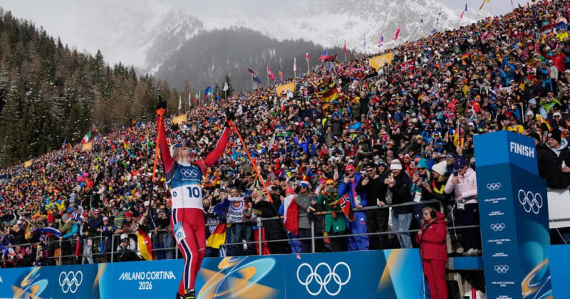 Norwegian biathlete Johannes Dale-Skjevdal crosses finish line celebrating gold medal win at Milano Cortina Olympics