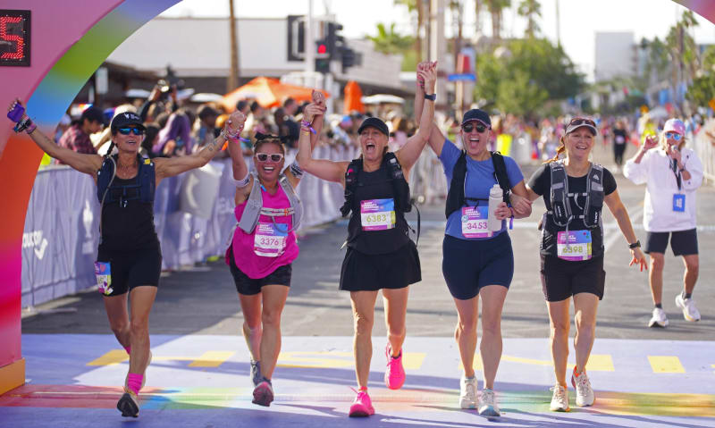 Group of diverse adults jogging together outdoors in morning sunlight, smiling
