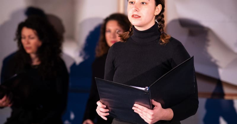 Theater actors performing Holocaust survivor stories on stage in intimate salon-style setting