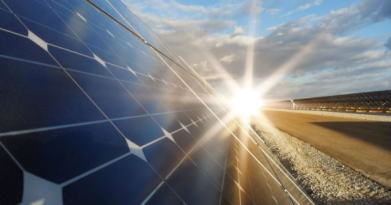 Modern solar panels on tracking systems in rural landscape with rolling hills under sunny sky