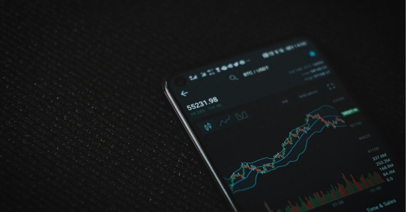 African entrepreneur using mobile phone with financial technology interface displaying market data and predictions