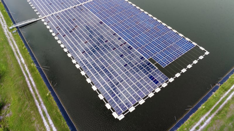 Solar panels gleaming in sunlight next to hydroelectric dam, representing solar surpassing hydro power