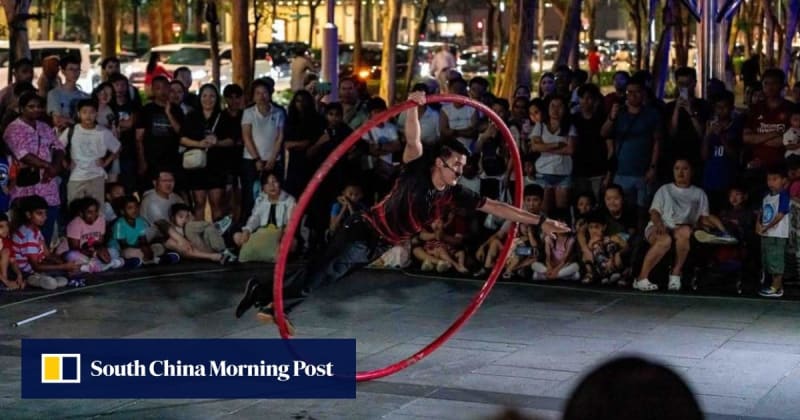 Street performer Bryan Wong doing circus act while former Singapore Prime Minister Lee Hsien Loong watches smiling