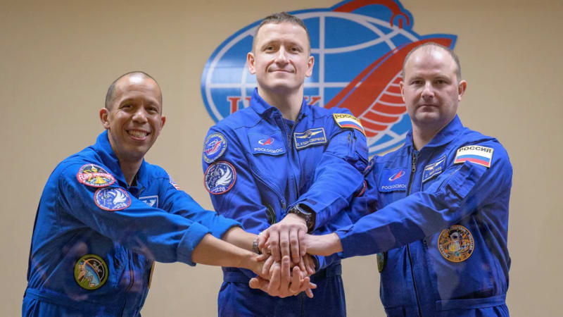 Three astronauts in blue flight suits pose together before their November 2025 ISS launch