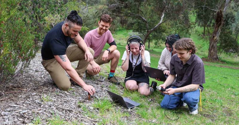 Researcher placing small microphone device into soil to record underground invertebrate sounds